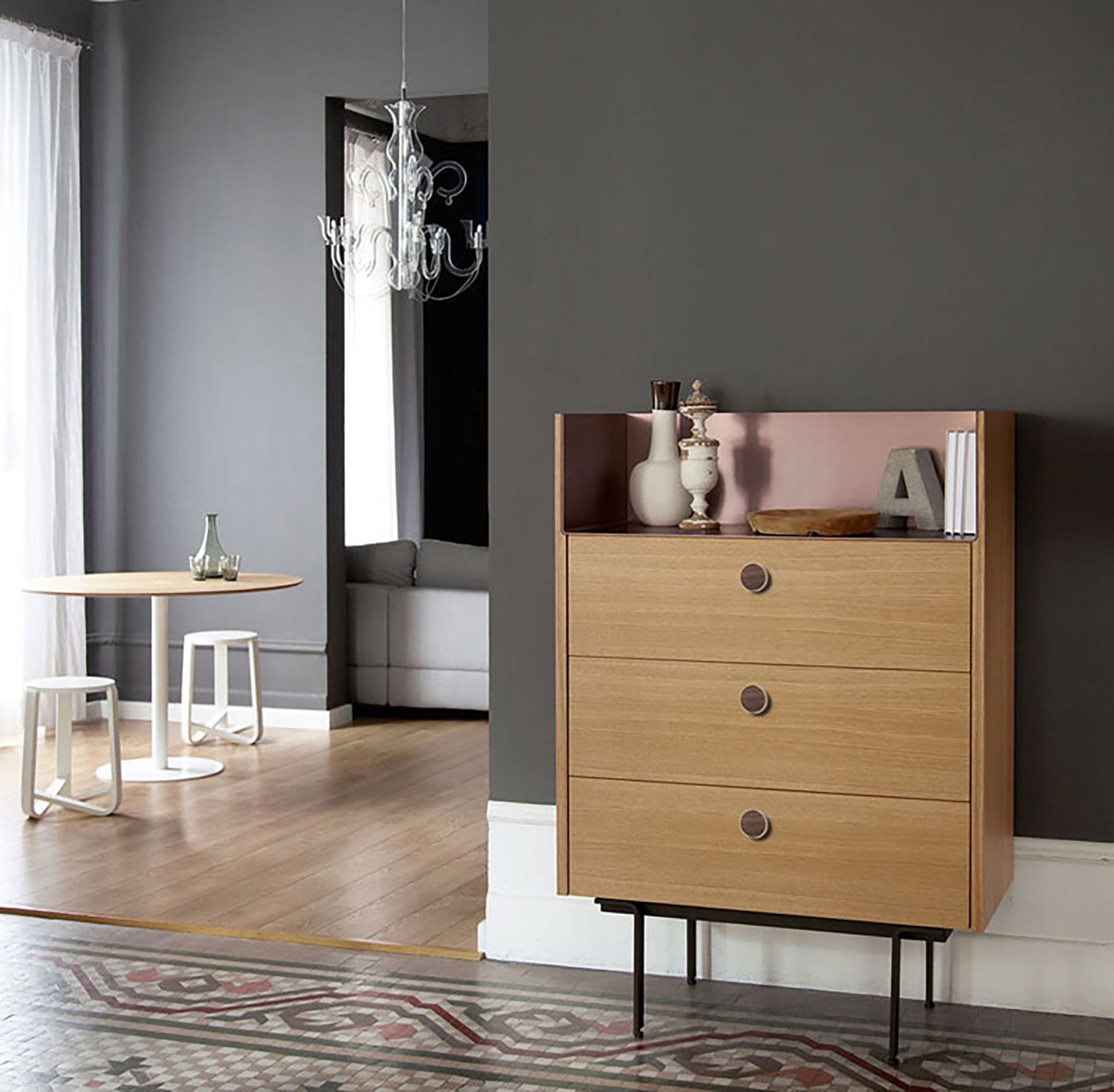 Wooden dresser with decorative items against a dark gray wall in a modern room.