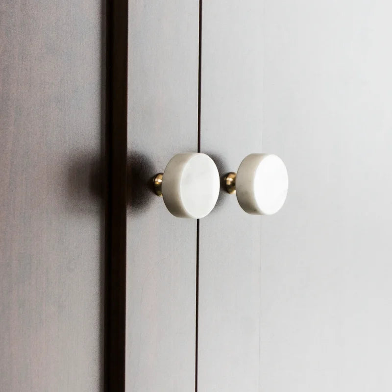 The Mantara M-0001 Theo Knob is a modern marble and brass knob in white, ideal for doors, drawers, and cabinets.