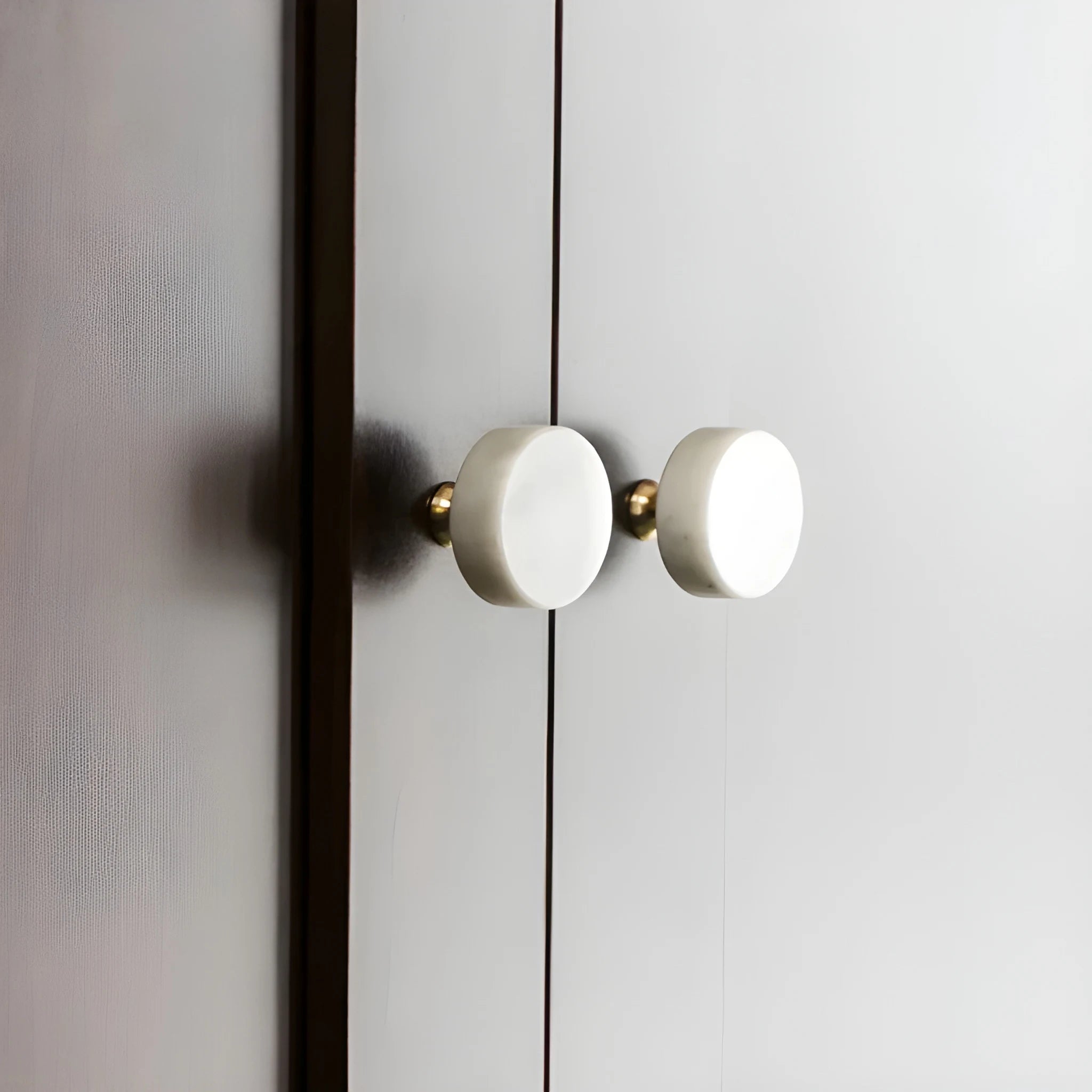 The Mantara M-0001 Theo Knob is a modern marble and brass knob in white, ideal for doors, drawers, and cabinets.