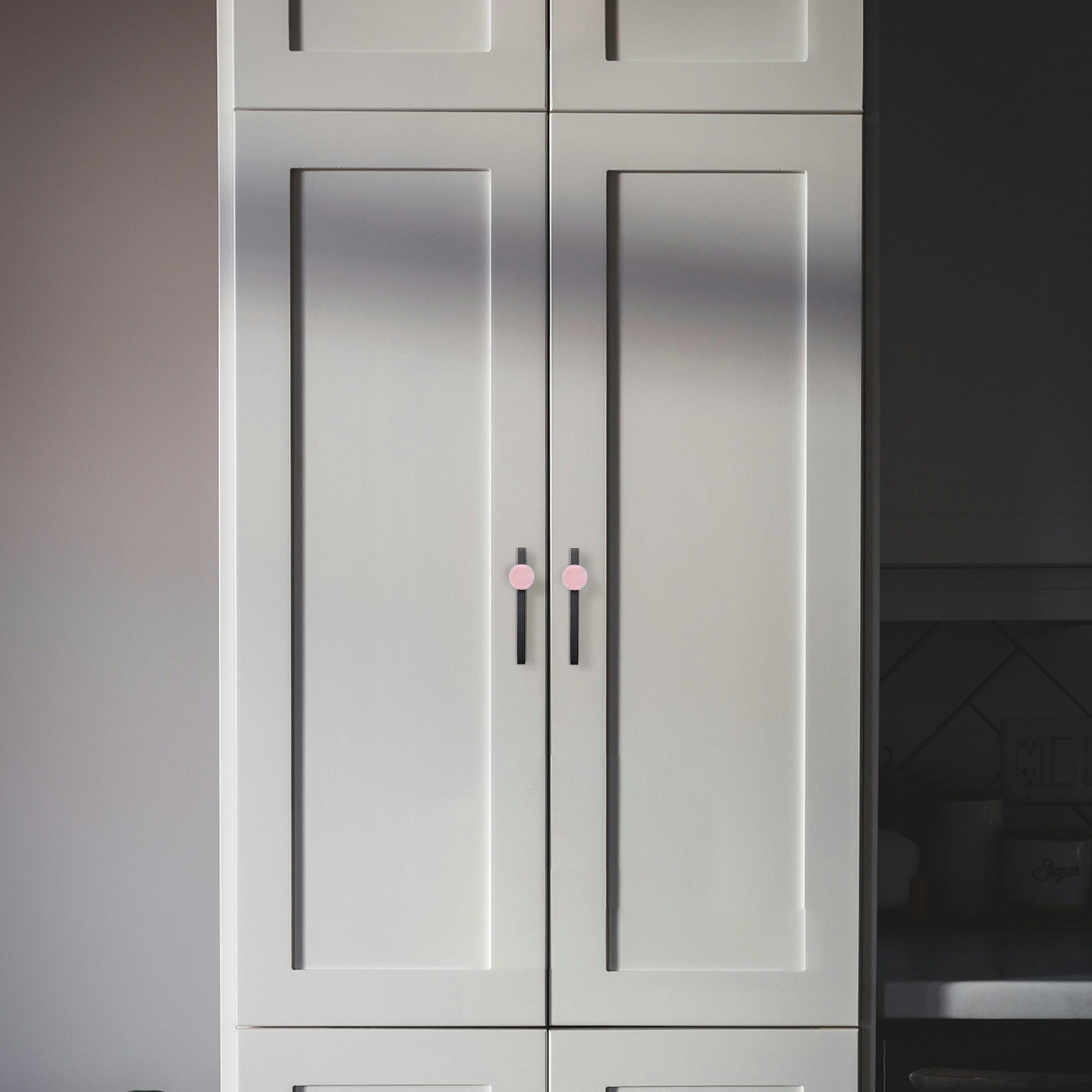 Gray cabinet with pink knobs in a kitchen setting, adding a soft pop of color to a modern space by Mantara.