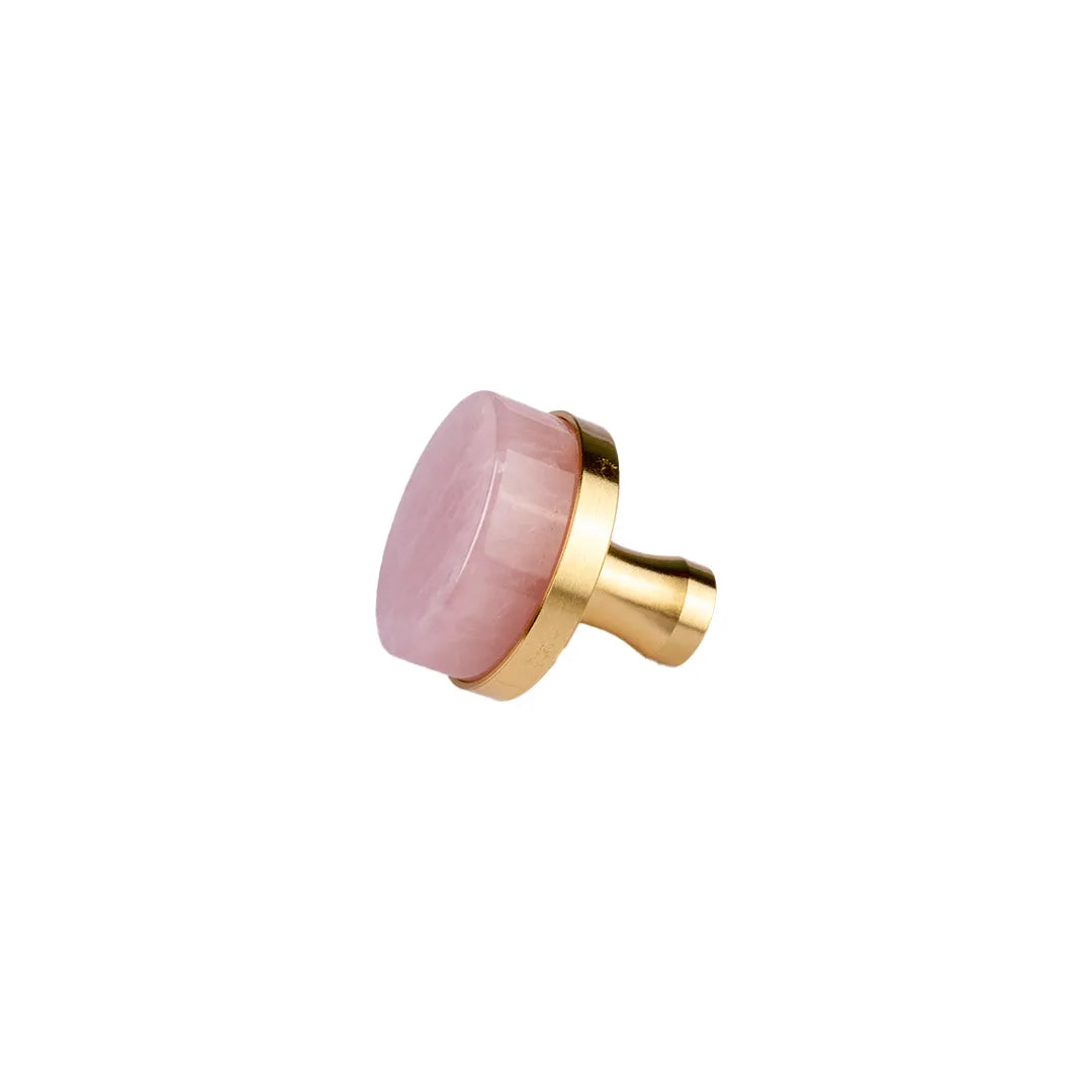 A modern cabinet knob featuring a round, polished pink stone top set in a brushed gold metal frame and cylindrical base, shown on a plain white background.