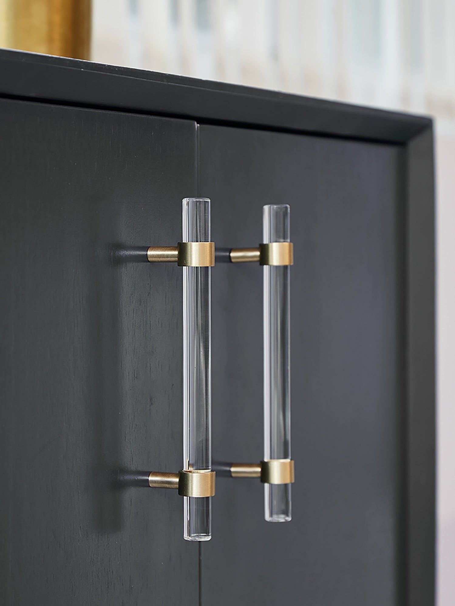 A sleek T-bar handle, Petra II made of clear acrylic with brushed brass supports in transparent white finish, model A-0008 by Mantara, A-0008.
