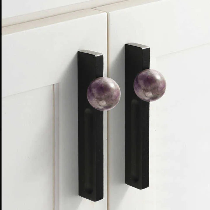 Cabinet doors with black handles featuring purple gemstone accents, set against a white background, by Mantara.