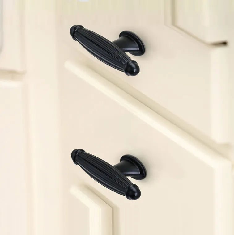 Black cabinet handles mounted on a white cabinet, offering bold contrast and modern appeal—designed by Mantara.