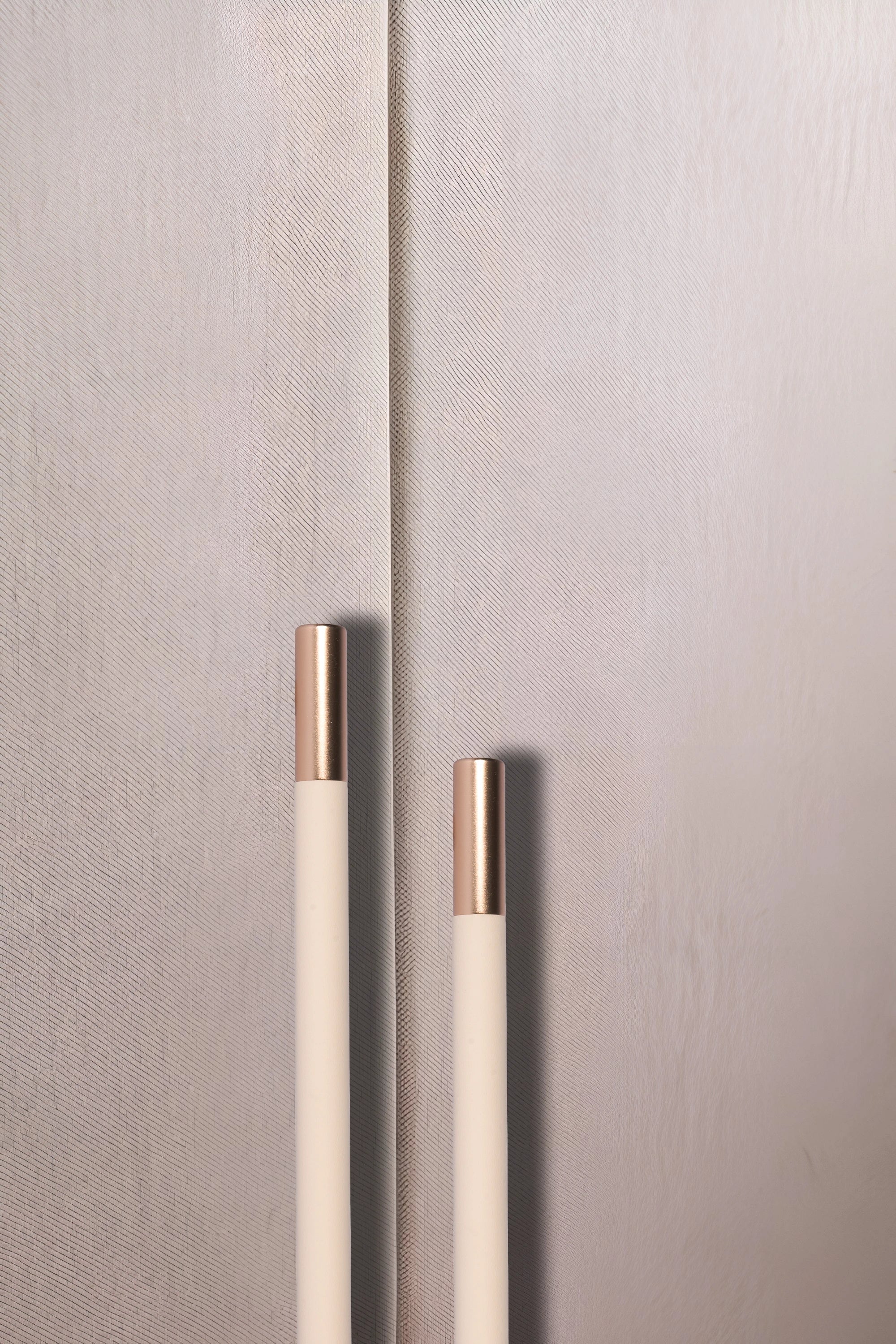 Close-up of a textured wall with two metallic handles, set against a neutral background, offering subtle detail by Mantara.