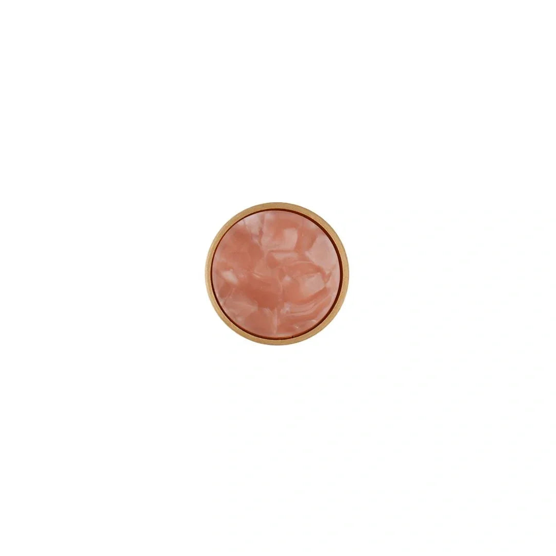 Round pink object with a gold rim on a white background