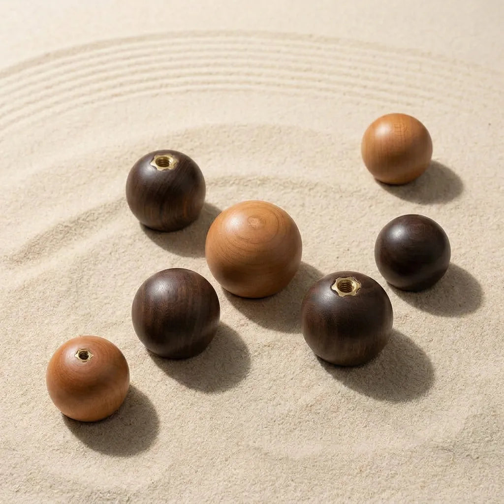 Seven wooden zen stones of varying sizes and tones, including light brown, medium tan, and dark brown, arranged on a bed of raked sand.