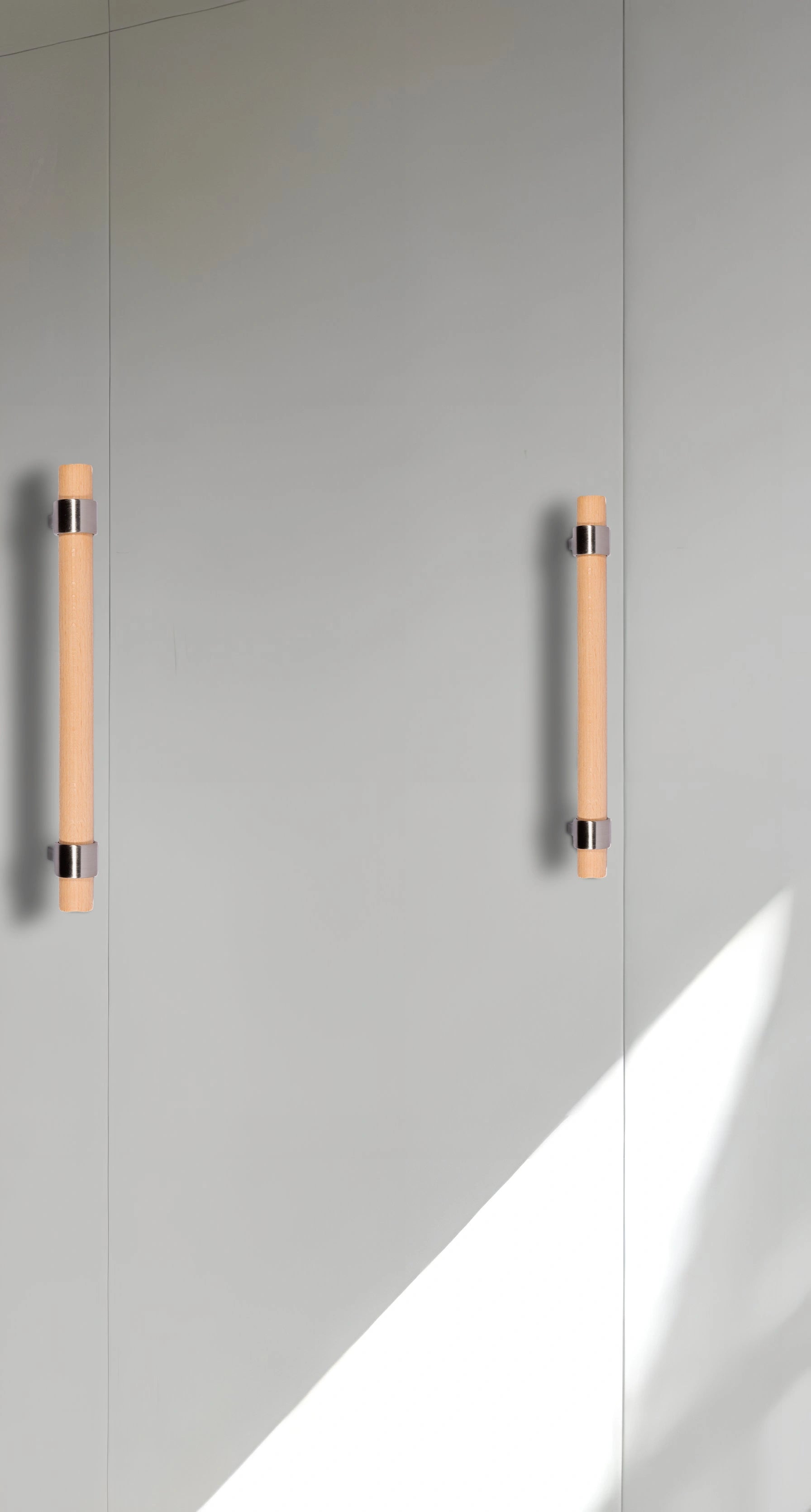Modern cabinet handles mounted on a light gray door, showcasing clean lines and subtle contrast—designed by Mantara