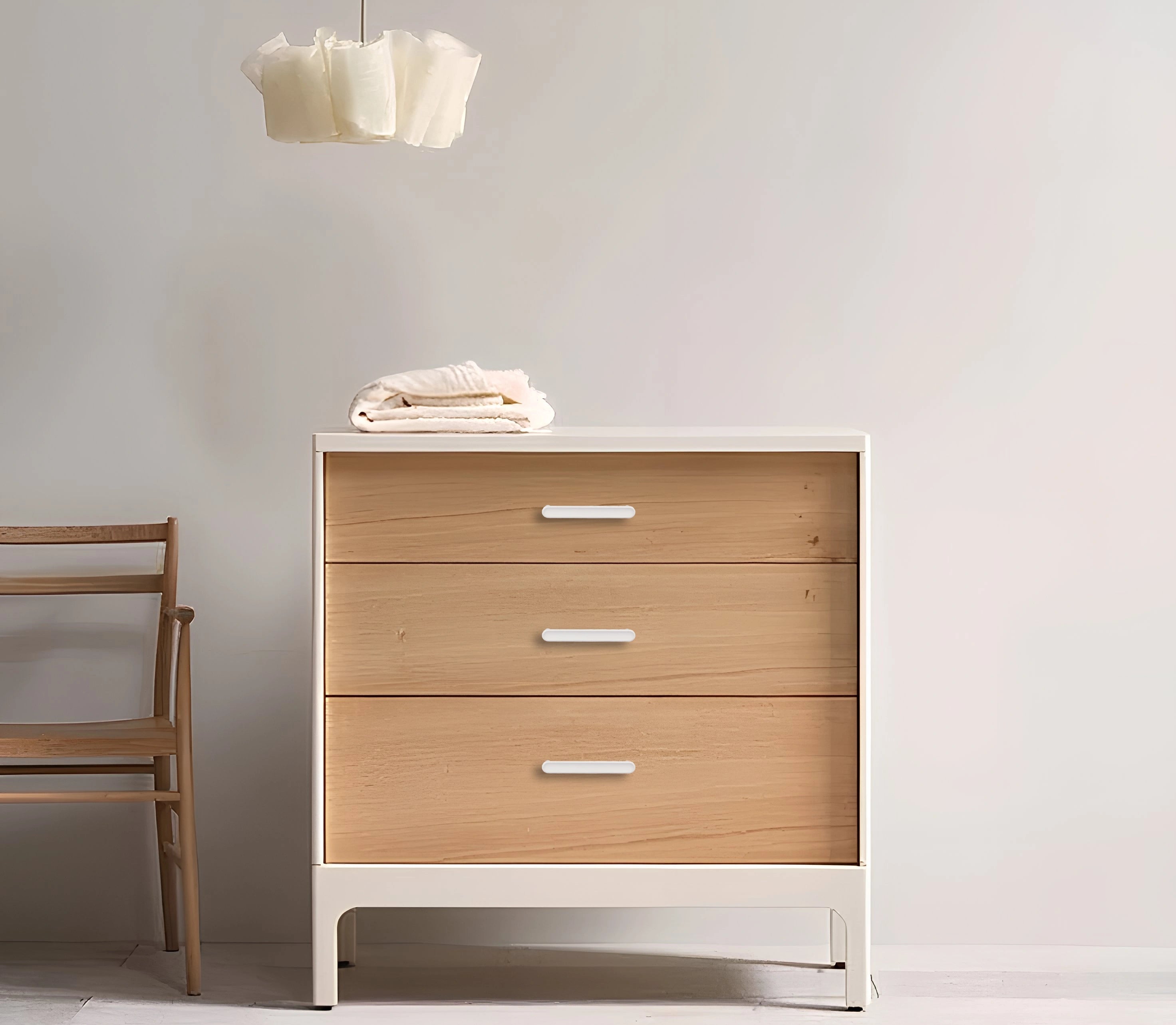 Wooden dresser with a white base and three drawers, set against a plain wall—clean, modern storage by Mantara.