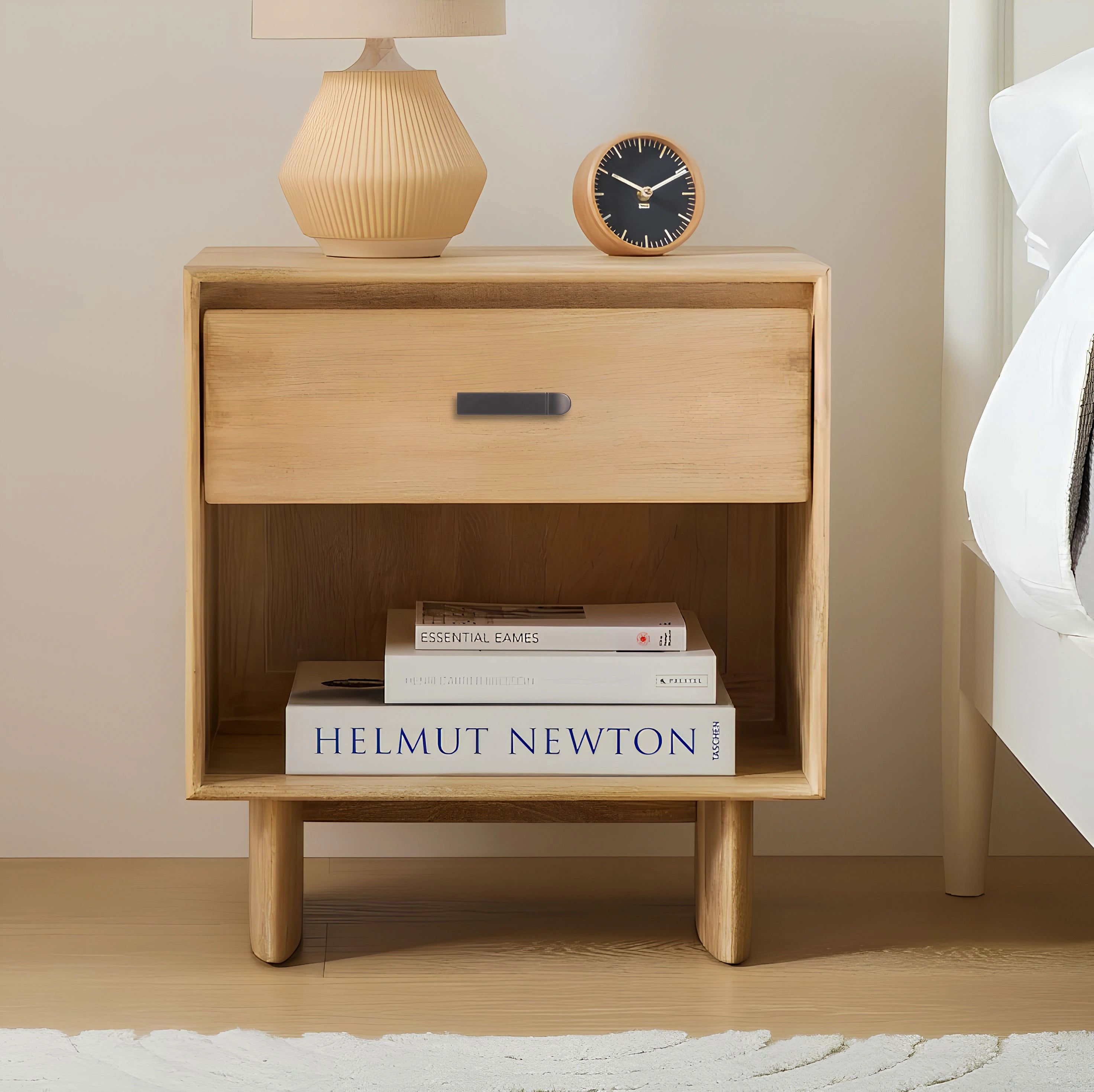 Wooden nightstand with a sleek handle, styled with books and a lamp against a neutral background—by Mantara.