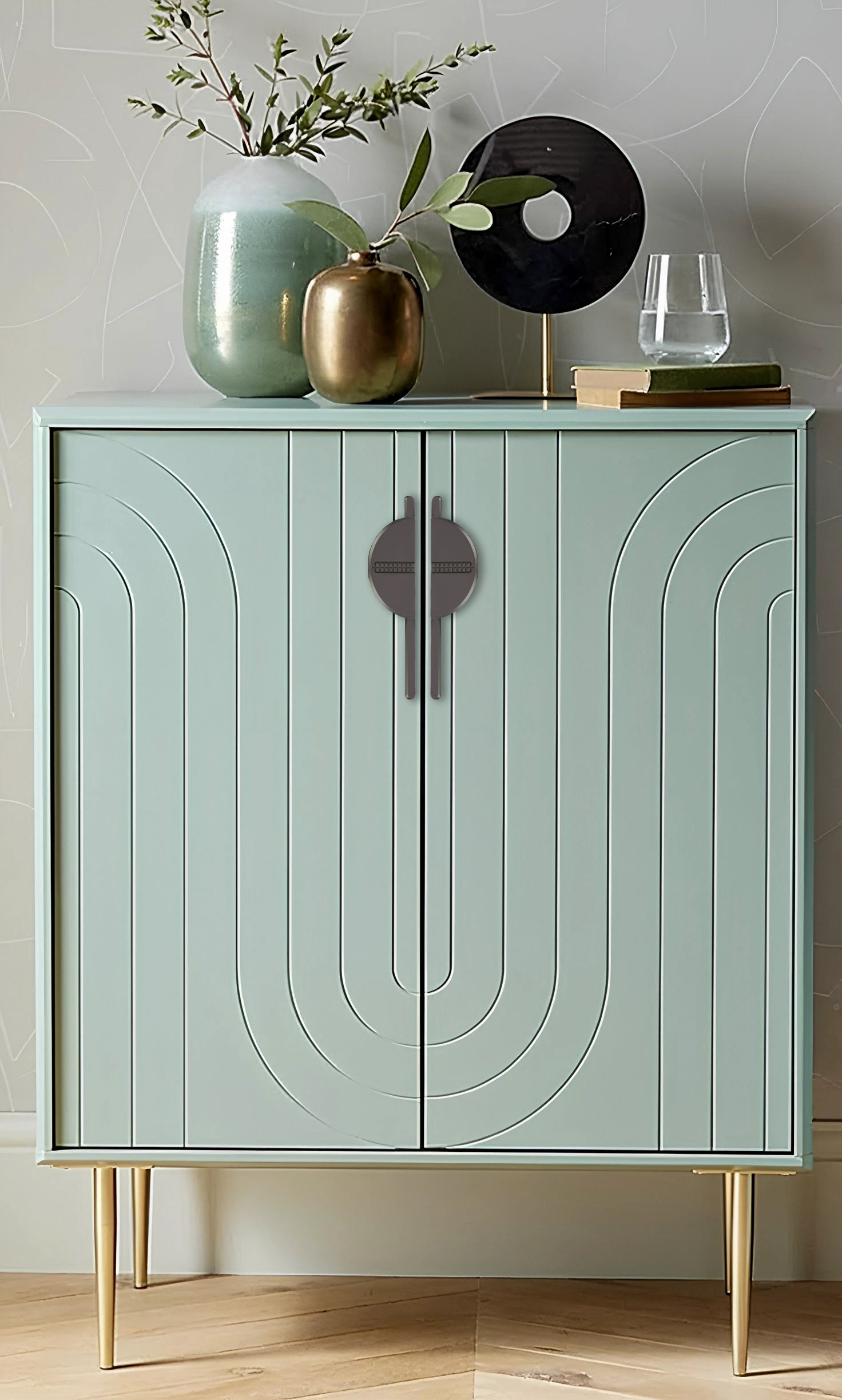 Light green cabinet with sleek handles, styled with decorative items against a light gray wall background—by Mantara.