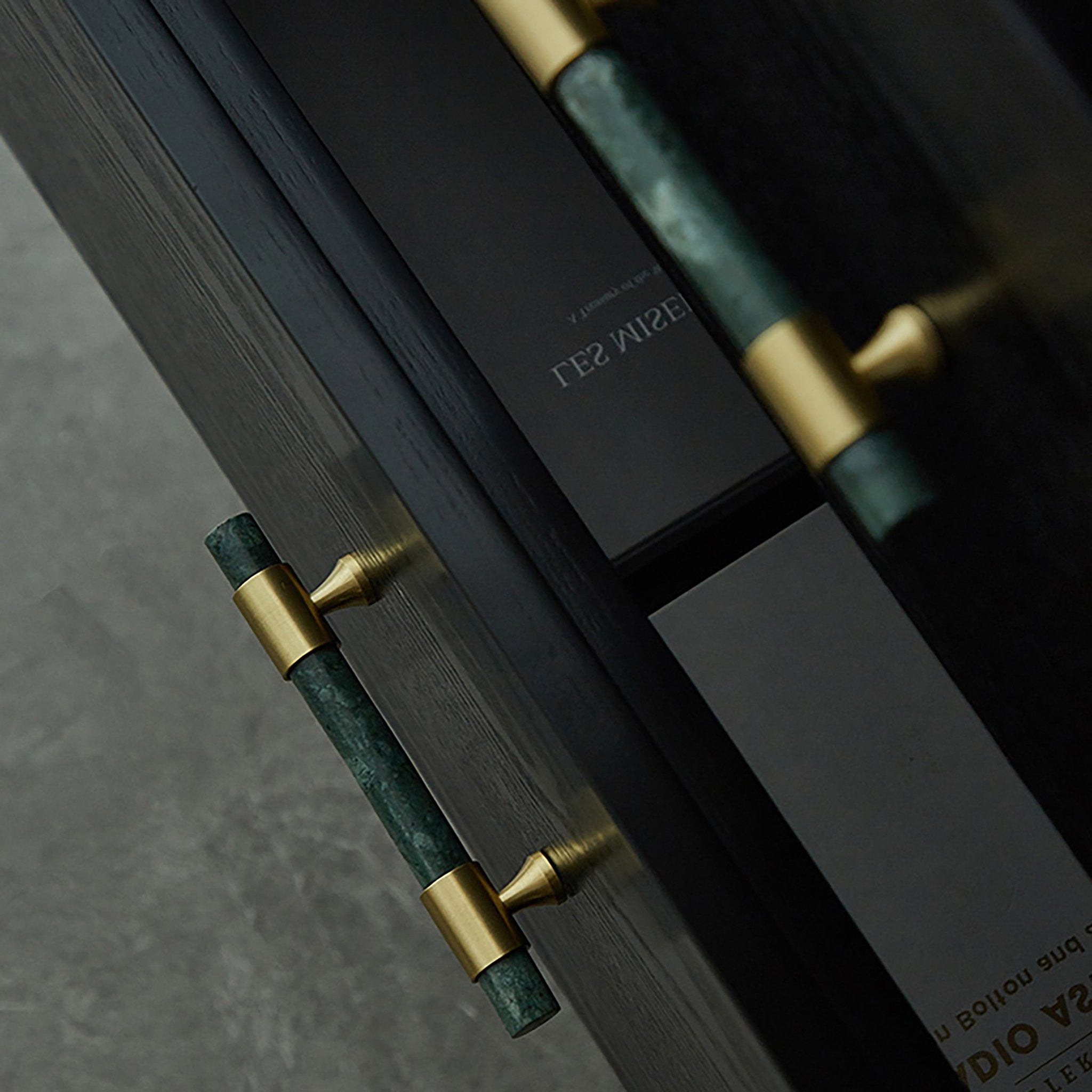 Close-up of a door handle with green and gold design on a dark surface, designed by Mantara