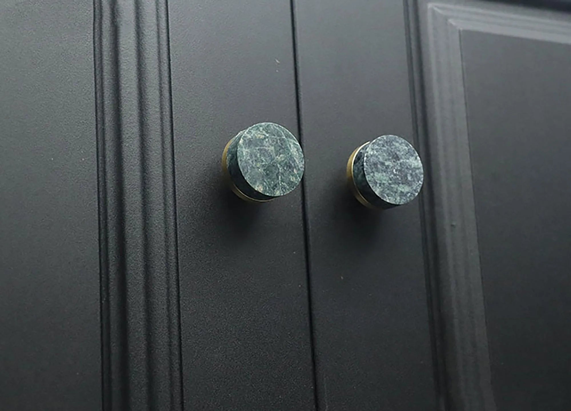 Two black cabinet knobs with green marble accents, highlighting a stylish and modern design detail by Mantara.