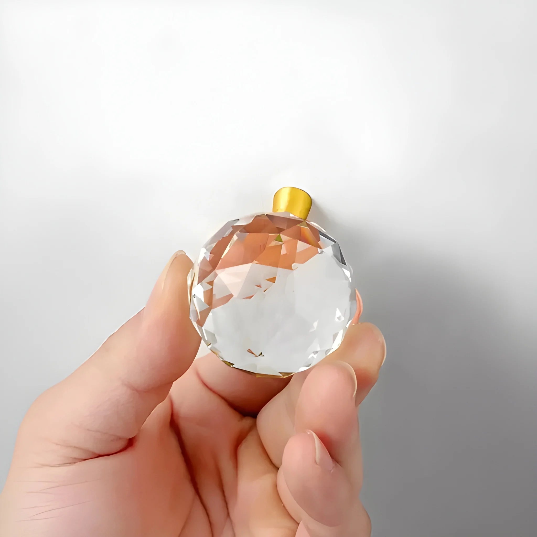 The Mantara C-0016 Quartz Handle is a modern crystal knob in white with polished brass, ideal for wardrobes, cabinets, and kitchens.