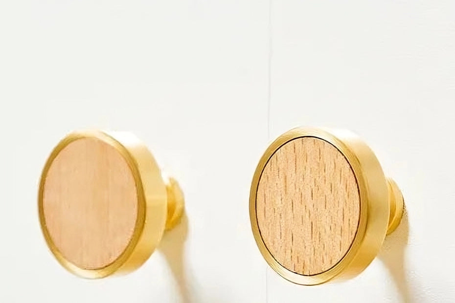 Pair of gold knobs with wooden centers, displayed on a clean white background—elegant contrast by Mantara.