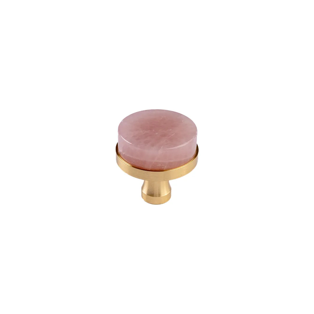 A round pink stone cabinet knob with a polished gold metal base, shown on a solid white background.