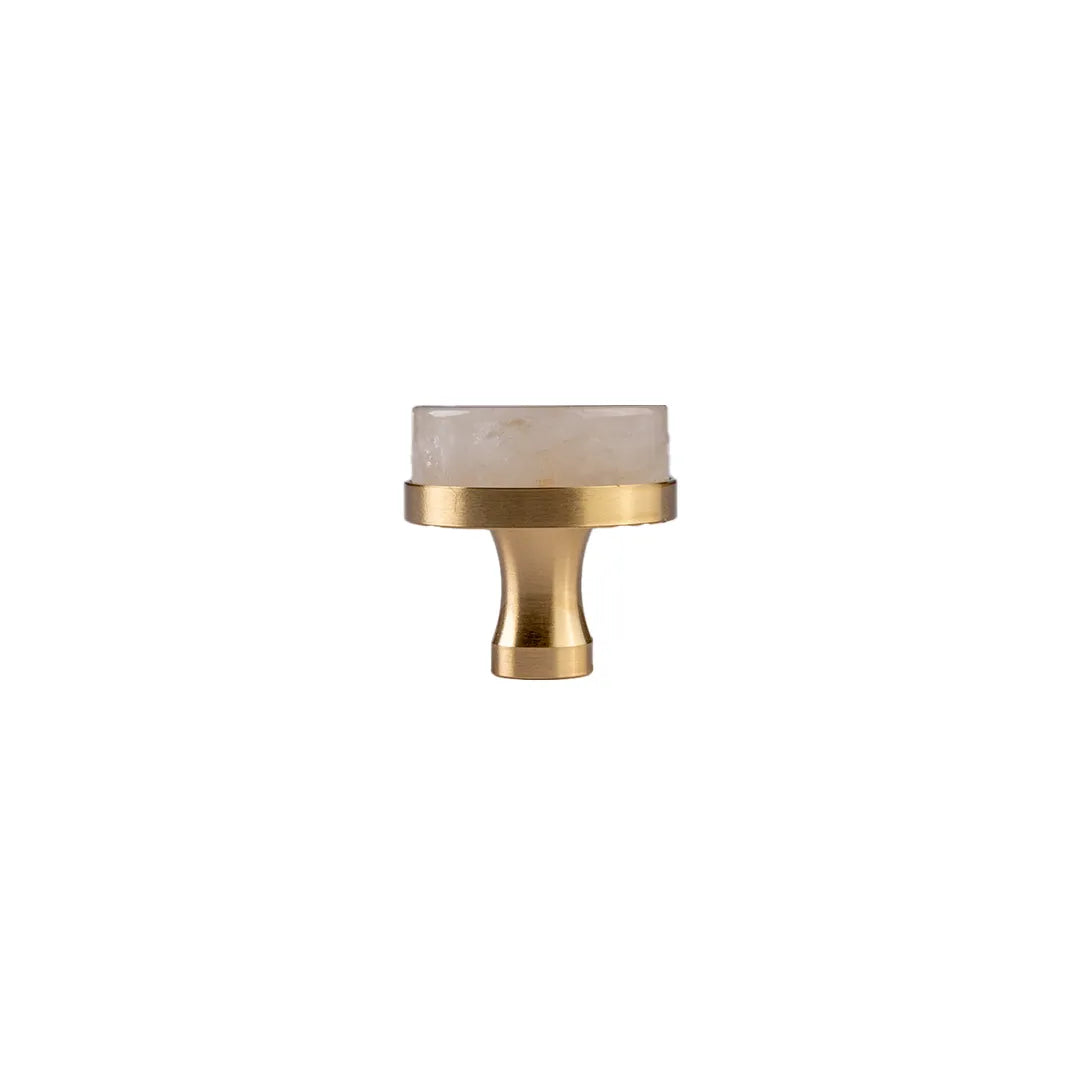 A modern cabinet pull handle featuring a brushed brass body and a rectangular white marble inlay on a solid white background.