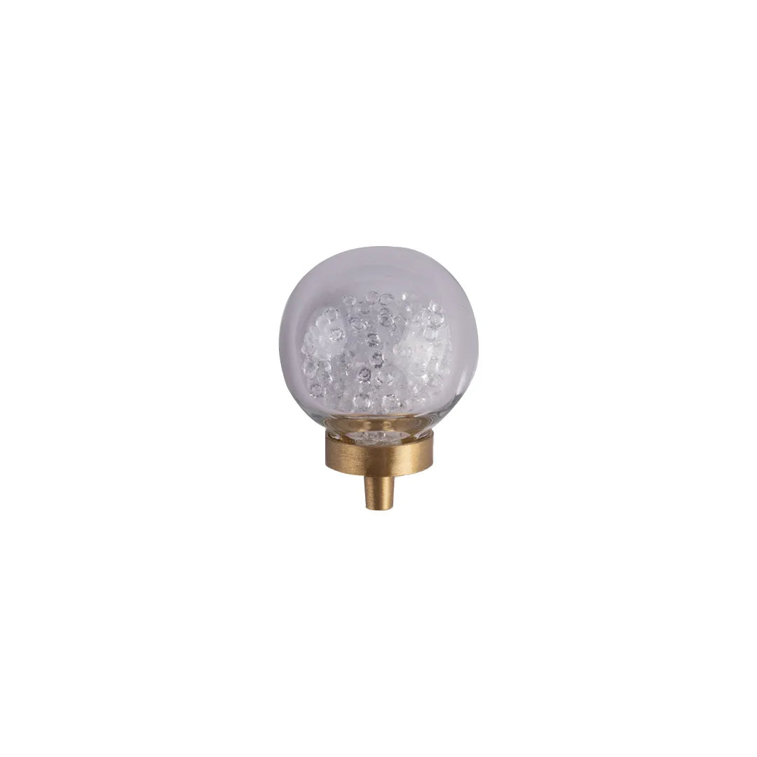 A spherical glass nightlight with a clear textured interior inside crystal and a gold brass base, shown against a plain white background.