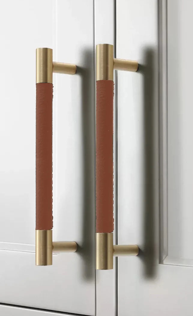 The Mantara L-0005 Sleek Leather Handle is a modern brass and leather handle in brown, ideal for wardrobes, drawers, and cabinets.