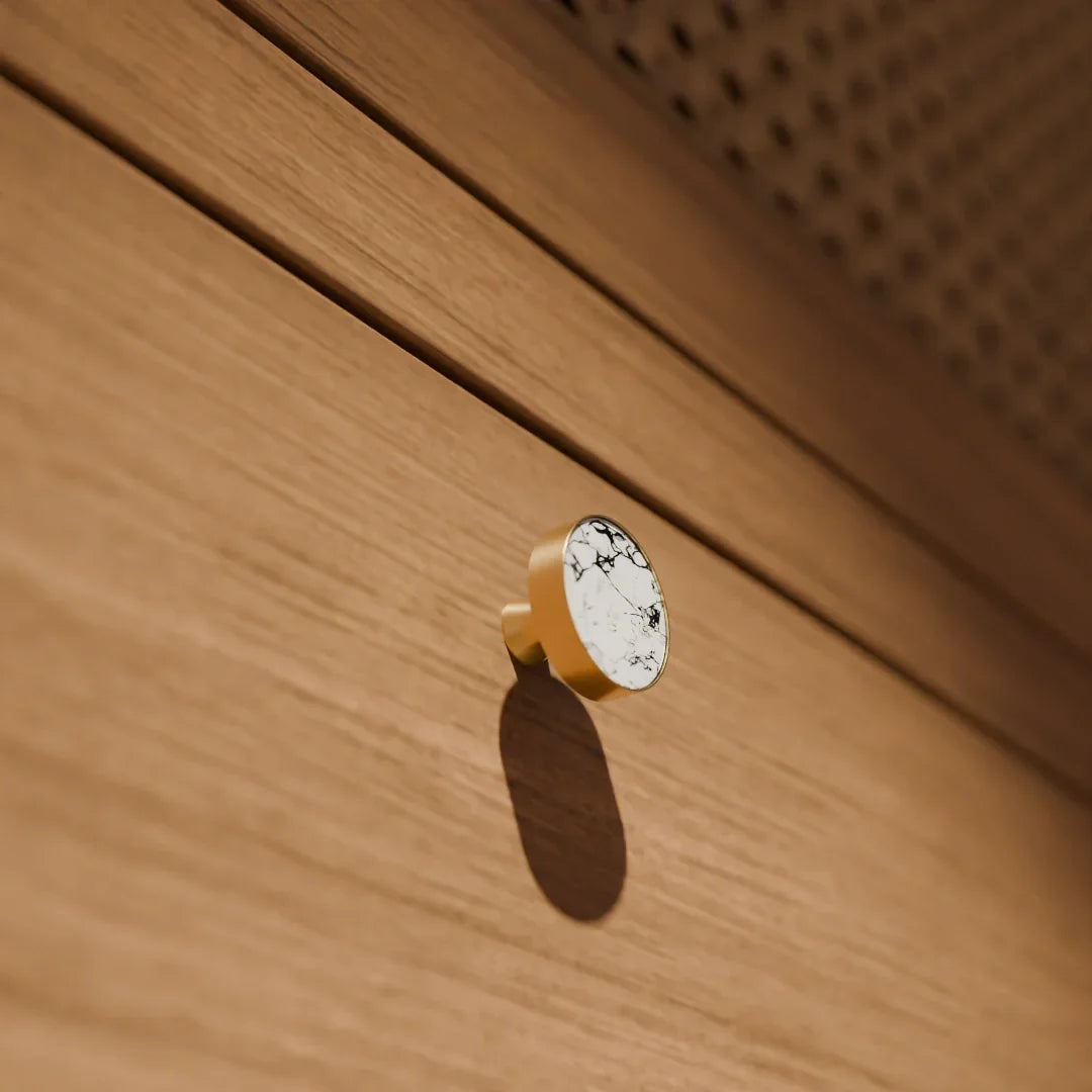The Mantara M-0004 Carrara Knob is a modern stone and brass knob in white, ideal for drawers and cabinets.