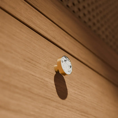 The Mantara M-0004 Carrara Knob is a modern stone and brass knob in white, ideal for drawers and cabinets.