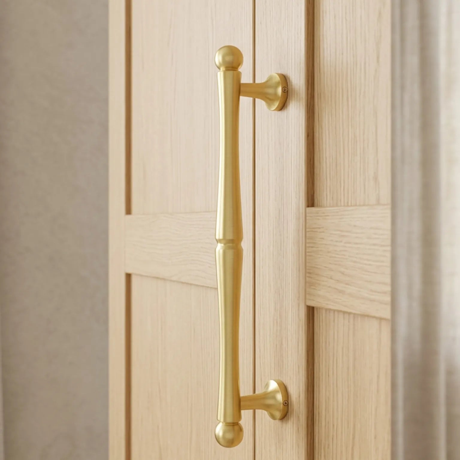A polished brass door handle with a classic bar design and ball finials, mounted on a light oak paneled door.