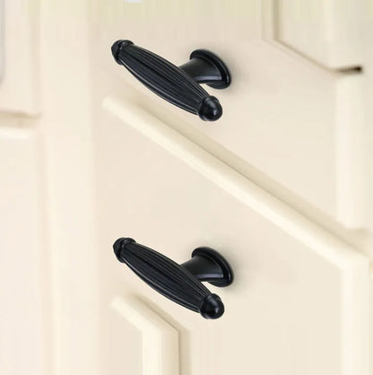 Black cabinet handles mounted on a white cabinet, offering bold contrast and modern appeal—designed by Mantara.