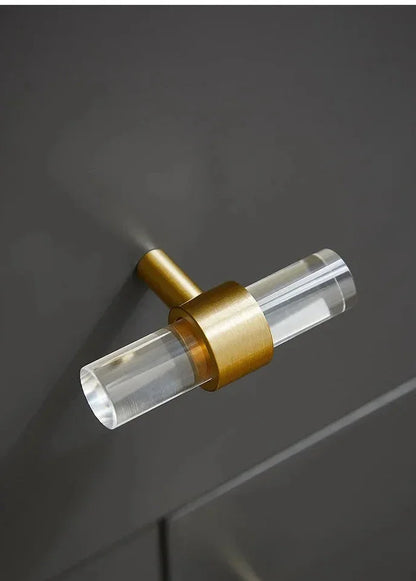 A sleek T-bar handle, Petra II made of clear acrylic with brushed brass supports in transparent white finish, model A-0008 by Mantara, A-0008.