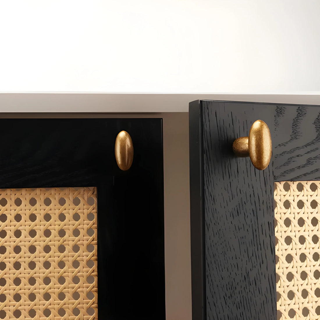 Close-up of a black cabinet with gold handles and woven pattern.