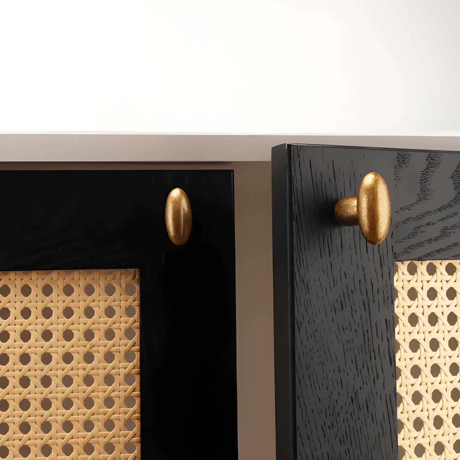 Close-up of a black cabinet with gold handles and woven pattern.