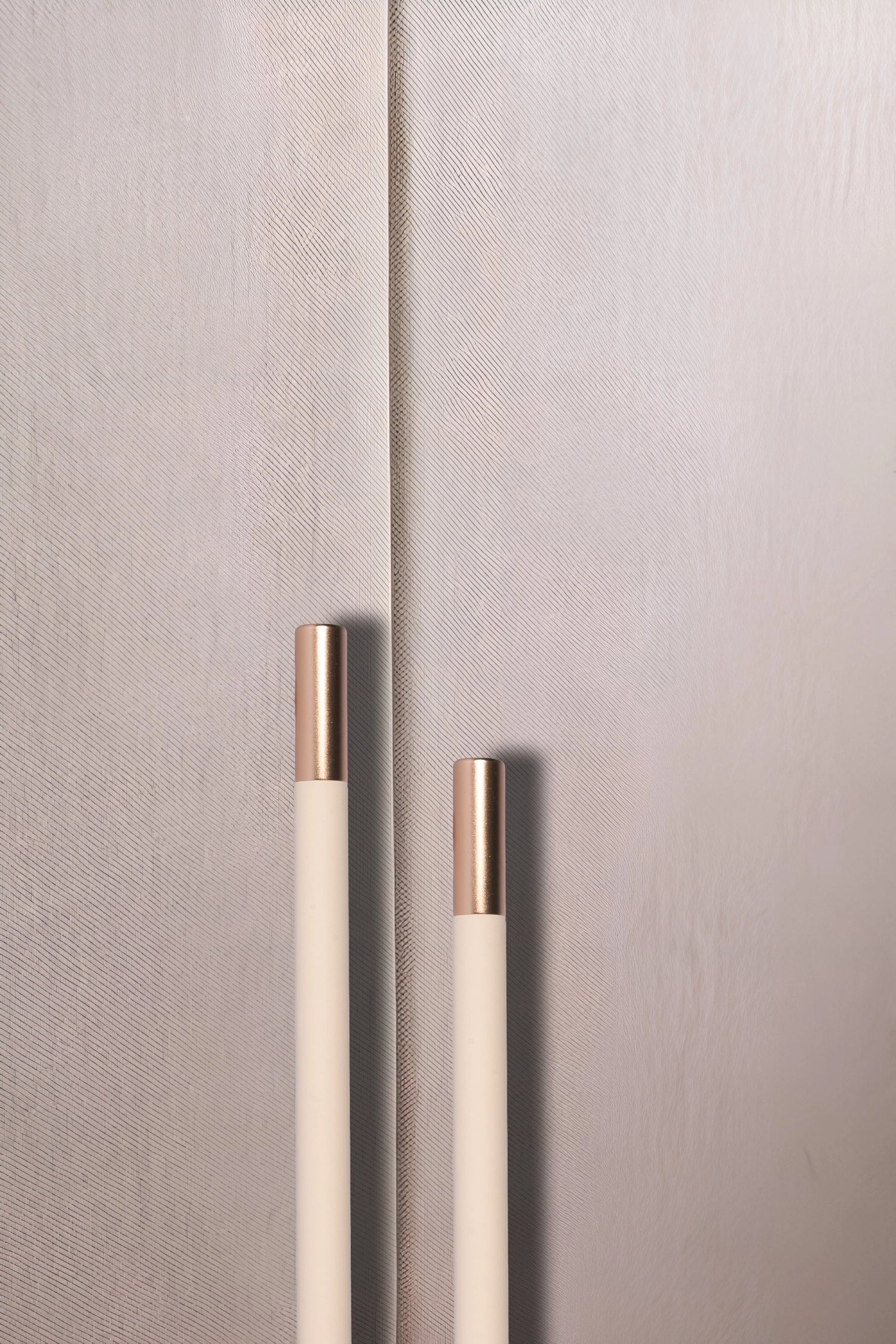 Close-up of a textured wall with two metallic handles, set against a neutral background, offering subtle detail by Mantara.