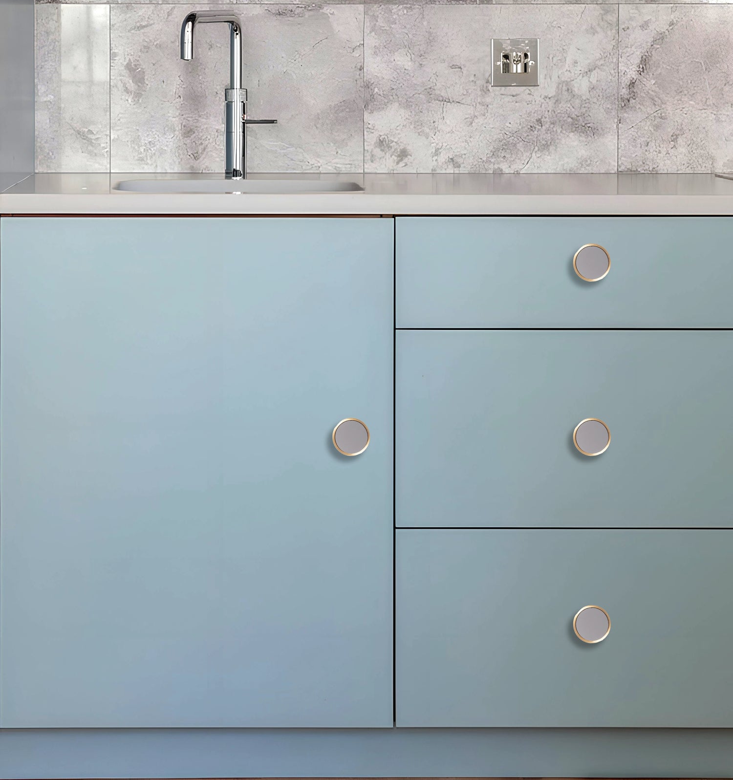 Kitchen cabinet with light blue doors and silver knobs, set against a white marble backsplash, styled by Mantara.