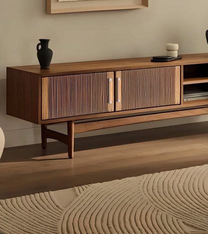 Wooden entertainment console with grey handles and decorative items, set against a soft beige wall—styled by Mantara.