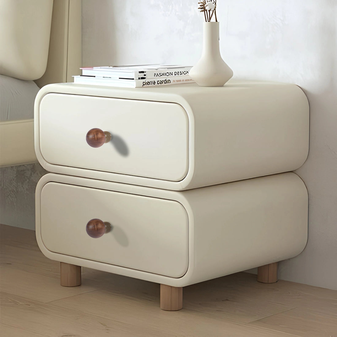 Beige nightstand with wooden drawers, legs, and subtle knobs, styled in a warm, minimal room setting—by Mantara.