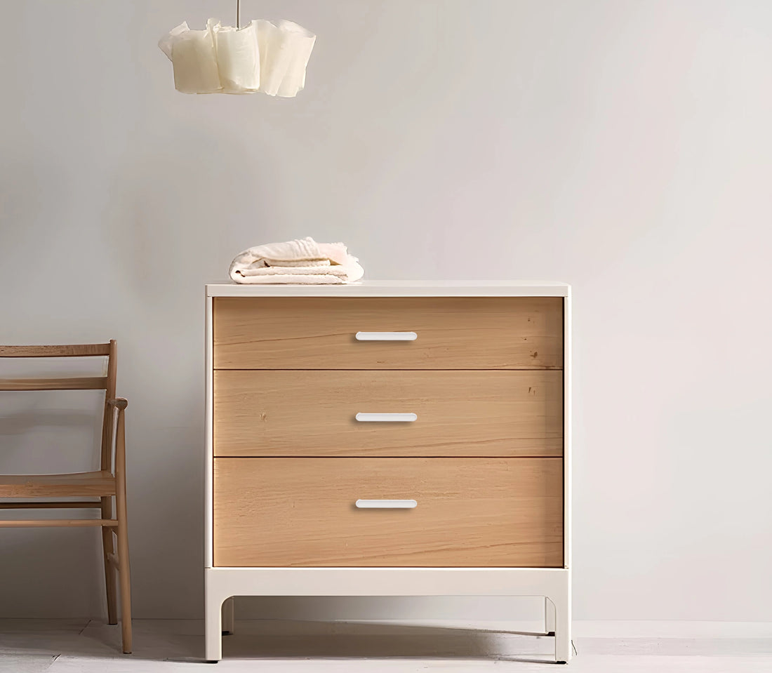 Wooden dresser with a white base and three drawers, set against a plain wall—clean, modern storage by Mantara.
