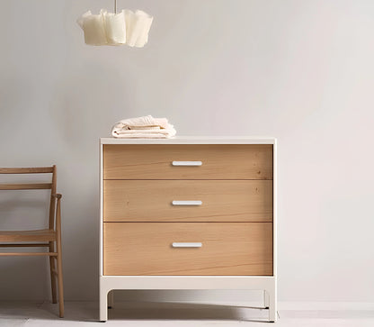 Wooden dresser with a white base and three drawers, set against a plain wall—clean, modern storage by Mantara.
