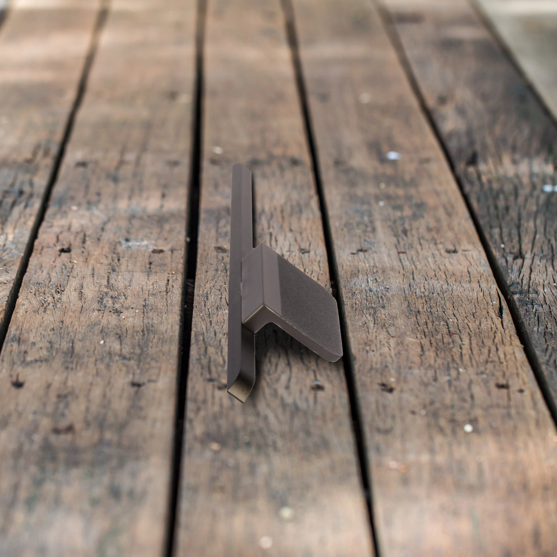 Dark metal bracket and a matching handle mounted on a wooden surface, highlighting bold, industrial design—by Mantara.