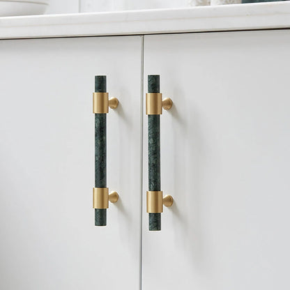 Pair of Arabella handles on a white cabinet—one vertical in green, one horizontal in brass—showcasing bold style by Mantara.