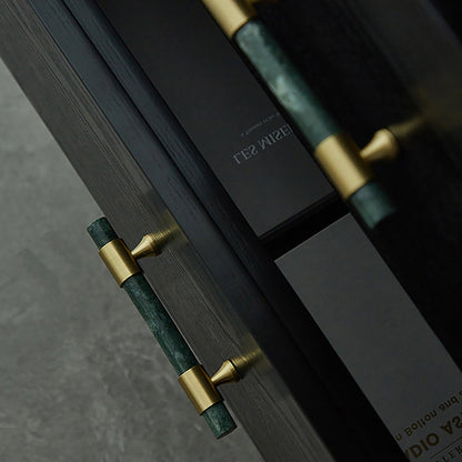Close-up of a door handle with green and gold design on a dark surface, designed by Mantara