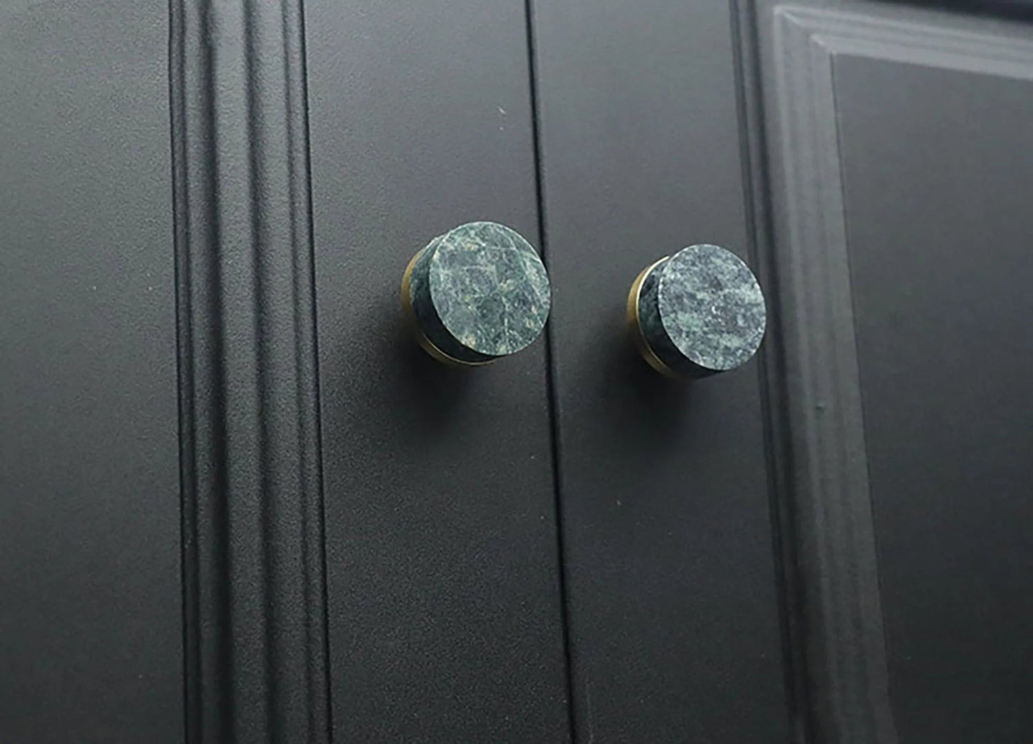 Two black cabinet knobs with green marble accents, highlighting a stylish and modern design detail by Mantara.