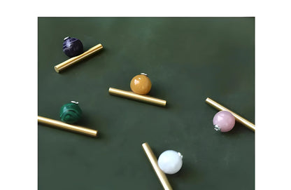 The Mantara C-0020 Chroma T-Bar is a modern crystal and brass knob in pink, purple, green, and white, ideal for drawers and cabinets.