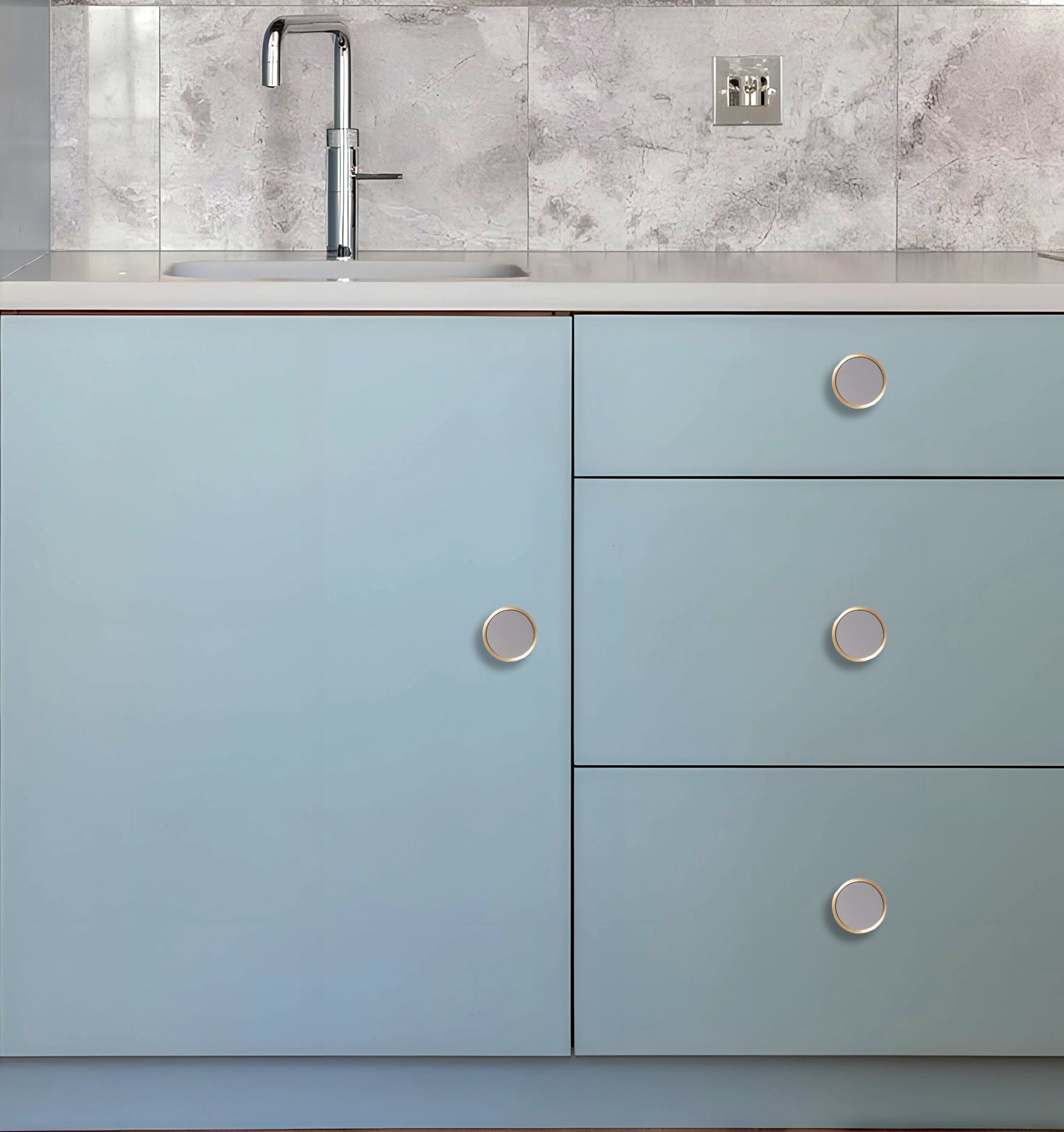 Kitchen cabinet with light blue doors and silver knobs, set against a white marble backsplash, styled by Mantara.