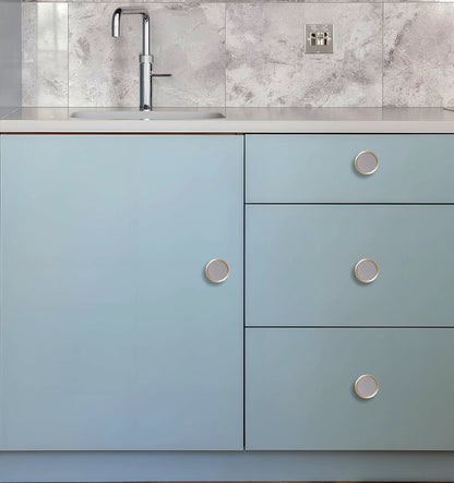 Kitchen cabinet with light blue doors and silver knobs, set against a white marble backsplash, styled by Mantara.