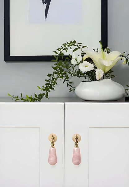 The Mantara C-0007 is a modern natural crystal + brass drop knob in pink, ideal for wardrobes and drawers.