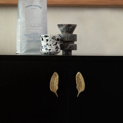 The Mantara B-0008 Quill Knob is a modern solid brass knob in brushed gold, available in left &amp; right designs for wardrobes, doors, and cabinets.