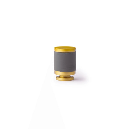 The Mantara L-0003 Tanner Knob is a modern brass and leather knob in grey, perfect for cabinets and furniture.