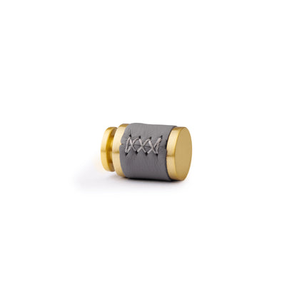 The Mantara L-0003 Tanner Knob is a modern brass and leather knob in grey, perfect for cabinets and furniture.