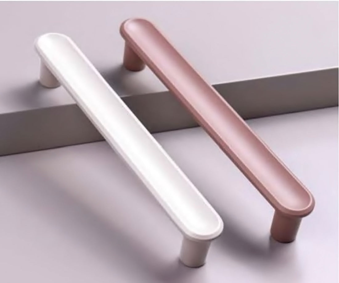 Two cabinet handles in pink and white, placed parallel on a grey surface—soft tones with modern symmetry by Mantara.